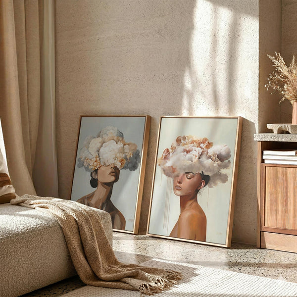 Two framed acrylic paintings of women with clouds obscuring their heads leaning against a textured wall.